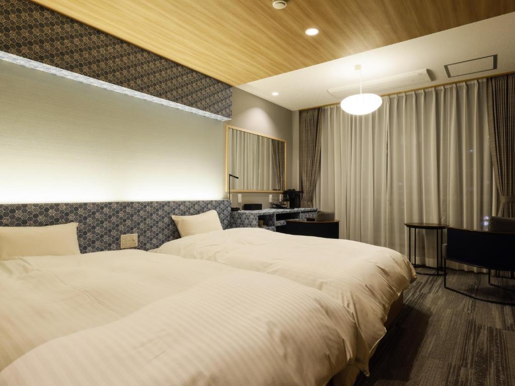 a hotel room with two beds and a desk at Ohashikan in Matsue