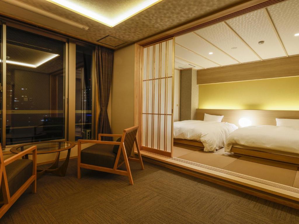 a hotel room with a bed and a desk and a window at Ohashikan in Matsue