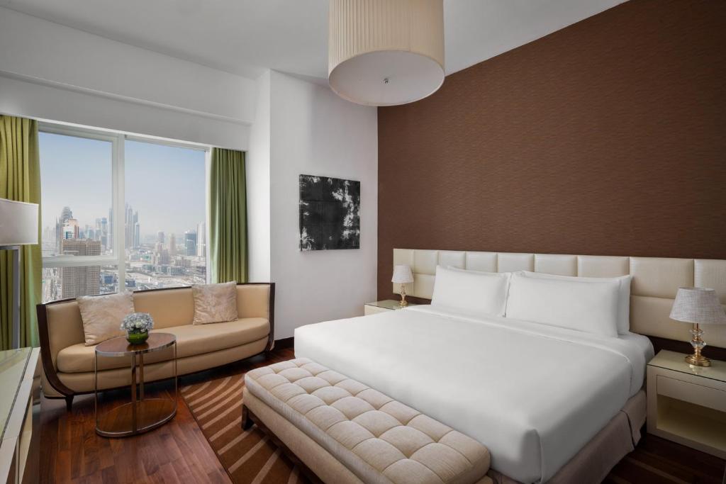 sypialnia z dużym białym łóżkiem i kanapą w obiekcie La Suite Dubai Hotel & Apartments w Dubaju