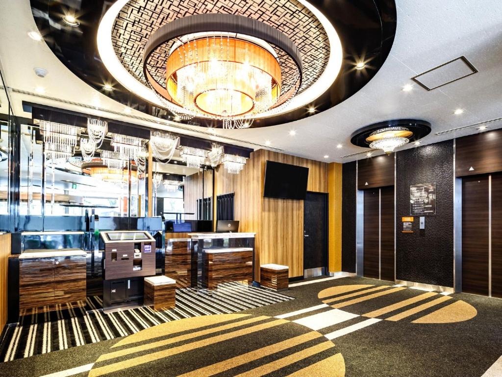 a lobby with a bar with a chandelier at APA Hotel Nagasaki Dejima in Nagasaki