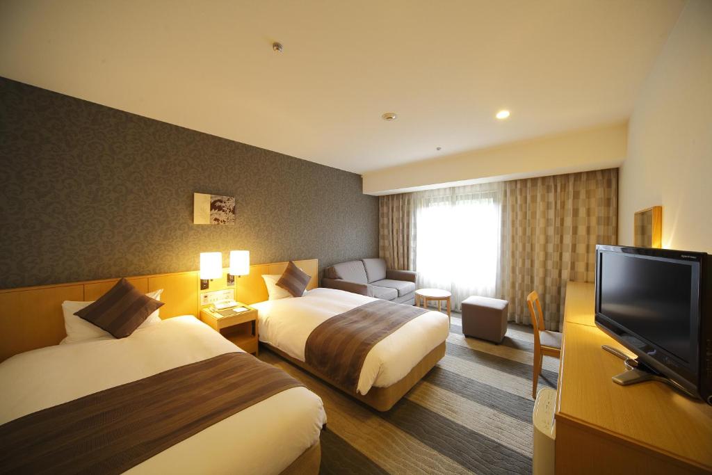 a hotel room with two beds and a flat screen tv at Hotel Granvia Wakayama in Wakayama