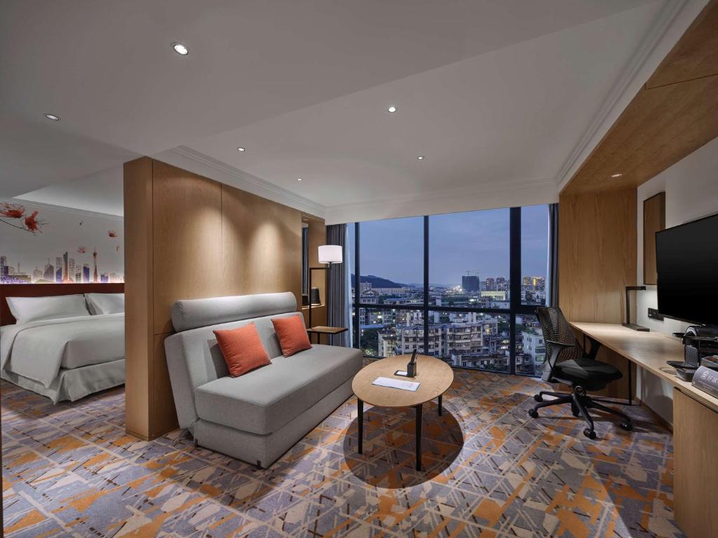 a hotel room with a couch and a bed at Hilton Garden Inn Guangzhou Tianhe in Guangzhou