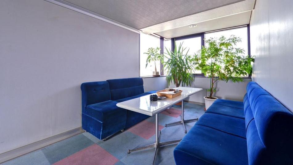 a room with blue chairs and a table and some plants at Business Inn Fukuyama in Fukuyama
