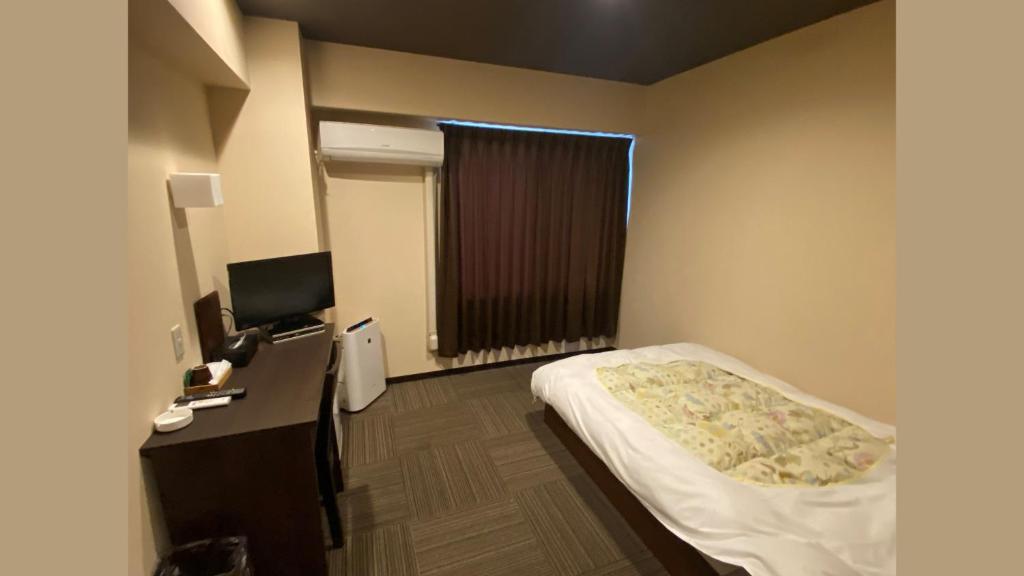 a small bedroom with a bed and a television at Business Inn Fukuyama in Fukuyama