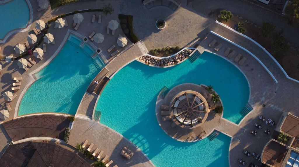 an overhead view of a pool with blue water at Lindian Village All Inclusive Resort Rhodes,Curio Collection in Kiotari