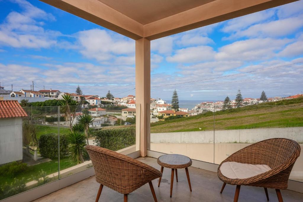 a patio with two chairs and a table on a balcony at Azenhas do Mar Valley House in Sintra