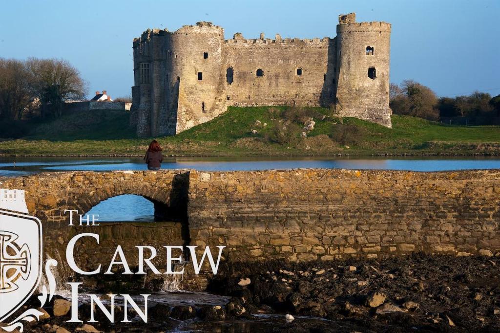 a castle on a hill with a person standing on a bridge at Carew Inn in Tenby