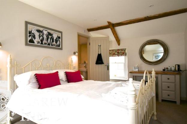 a white bed with red pillows in a bedroom at Carew Inn in Tenby