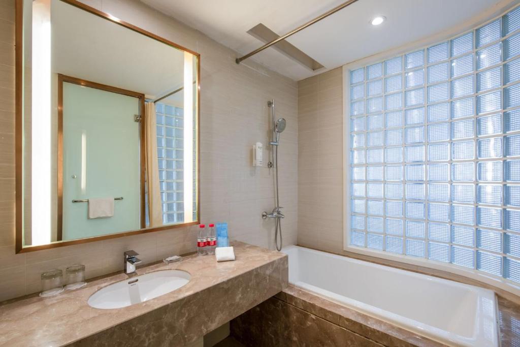 a bathroom with a sink and a tub and a mirror at Holiday Inn Express Shenyang Golden Corridor by IHG in Shenyang