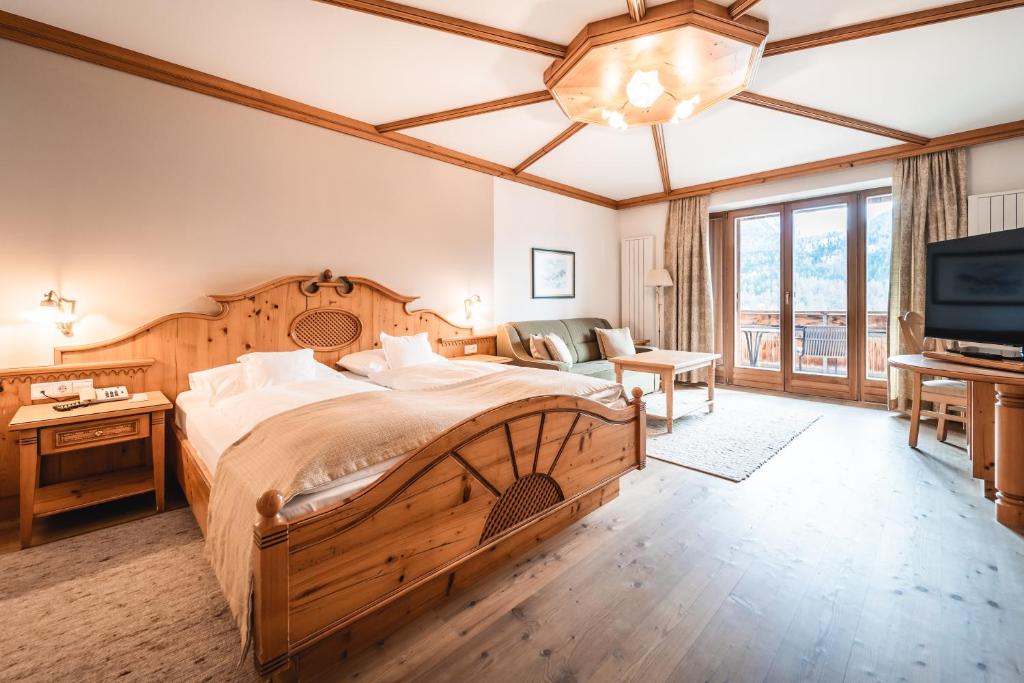 a bedroom with a large bed and a television at Naturhotel Leitlhof in San Candido