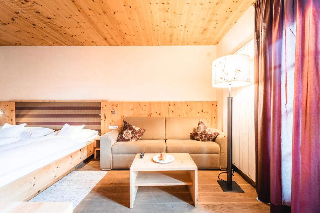 a bedroom with a bed and a couch and a table at Naturhotel Leitlhof in San Candido