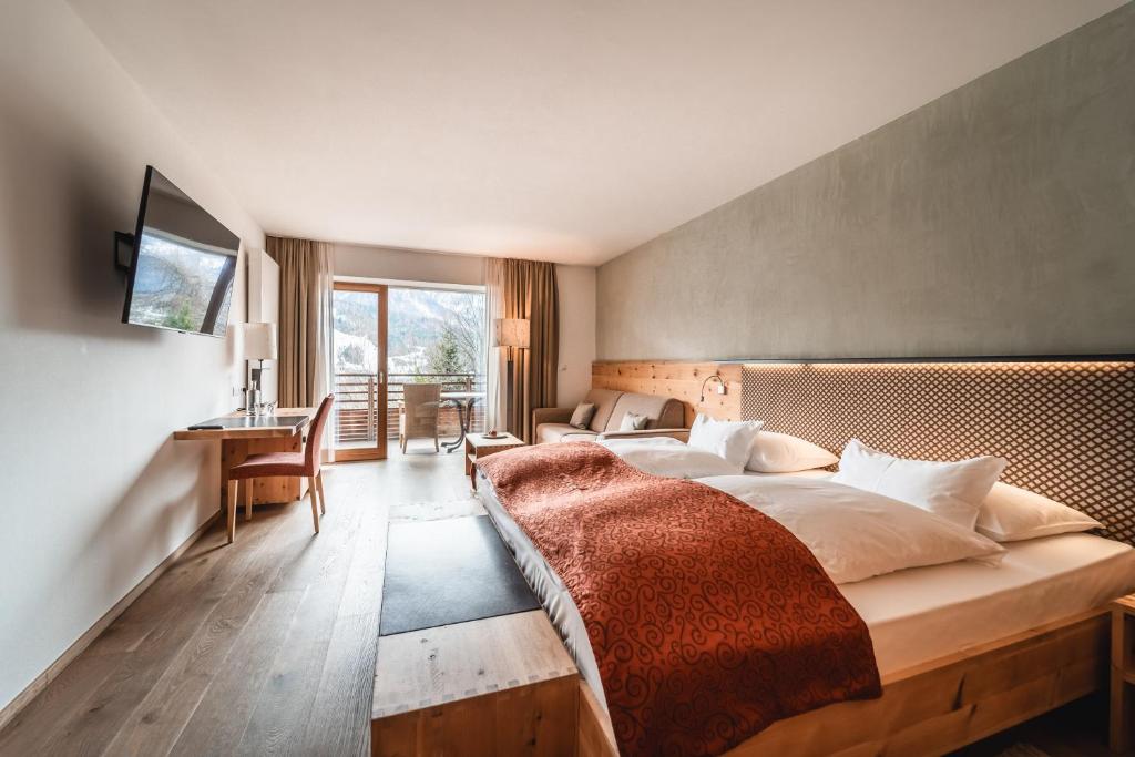 a bedroom with a large bed and a desk at Naturhotel Leitlhof in San Candido