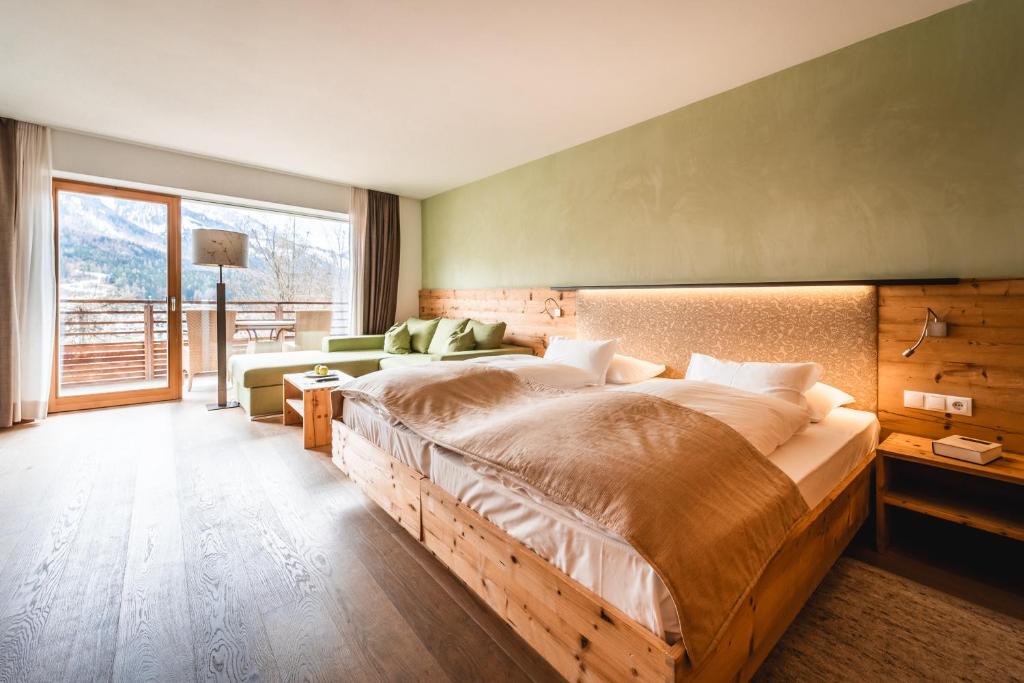a bedroom with a large bed and a large window at Naturhotel Leitlhof in San Candido