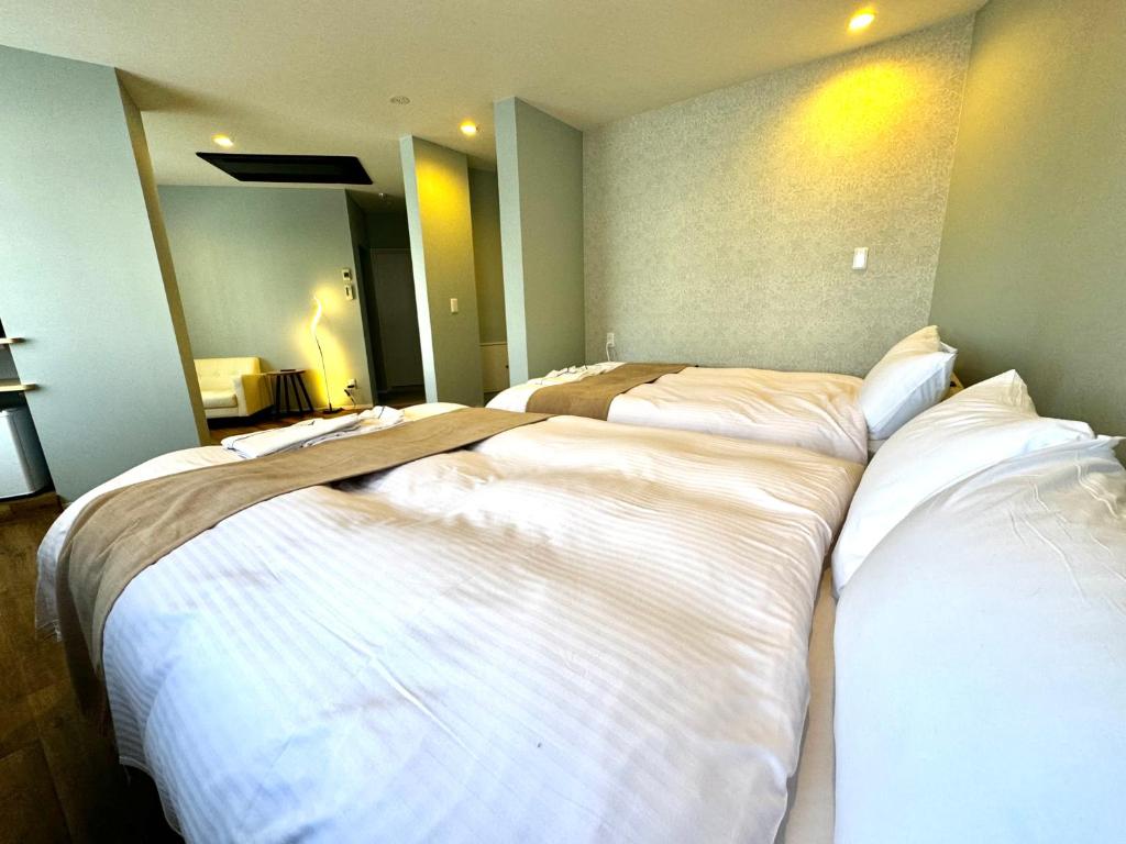 three beds are lined up in a room at Resort Stay Spa Tsurumi in Beppu