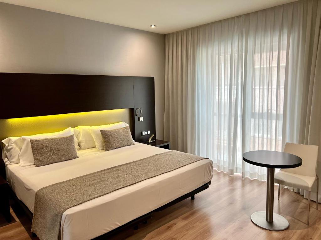 ein Schlafzimmer mit einem großen Bett und einem Tisch in der Unterkunft Turia Granada in Granada