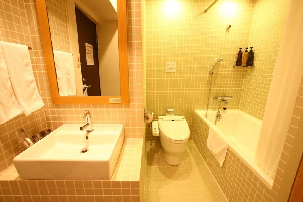 a bathroom with a sink and a toilet and a tub at Sutton Place Hotel Ueno in Tokyo