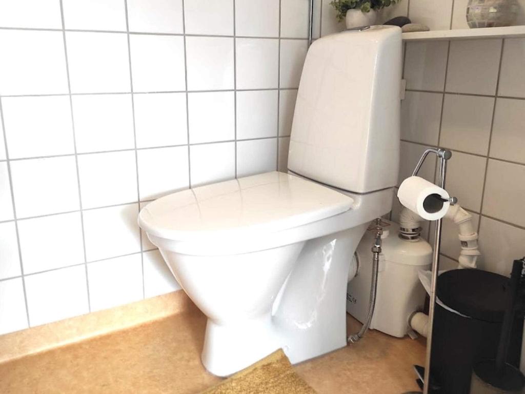 a white toilet in a white tiled bathroom at Holiday home BORÅS II in Borås