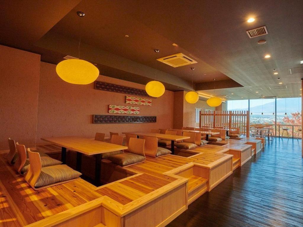 a restaurant with wooden tables and chairs and yellow lights at HOTEL CLAD in Fuji