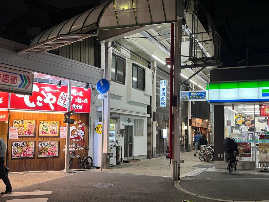 a group of shops on a city street at night at Osaka Kanzakigawa Royal駅徒步1分 "private house 3 bed rooms "一棟貸し宿 in Osaka