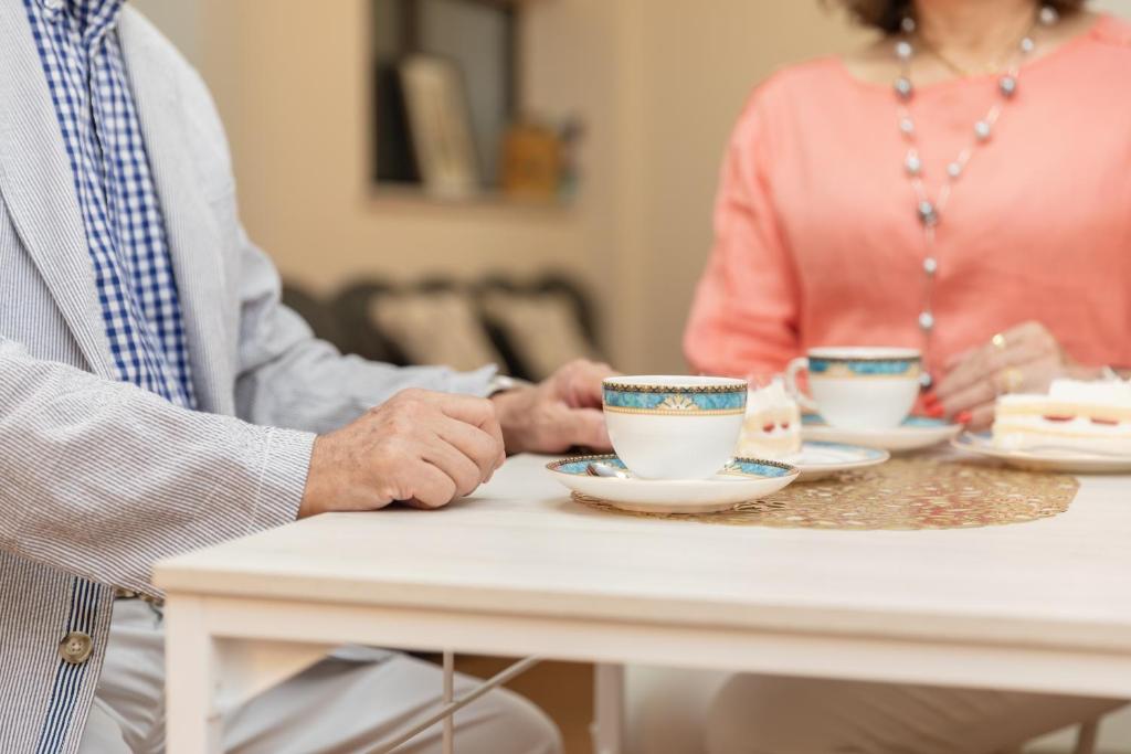 an older couple sitting at a table with cups of tea at Osaka Kanzakigawa Royal駅徒步1分 "private house 3 bed rooms "一棟貸し宿 in Osaka