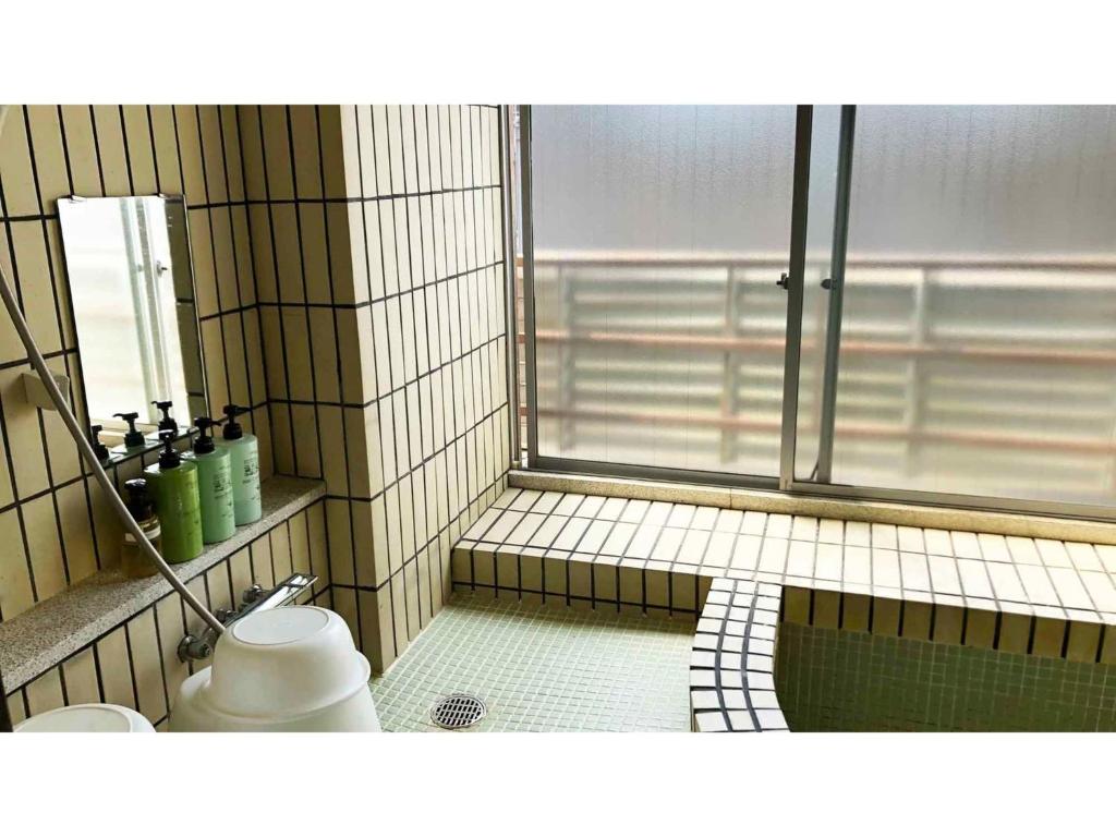 a tiled bathroom with a shower and a toilet at Kagetsu Ryokan - Vacation STAY 04882v in Shizuoka