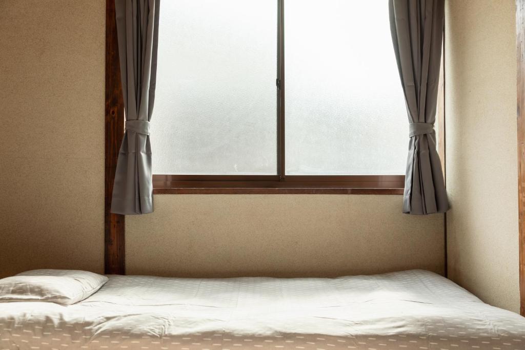 a bed in front of a window with curtains at Osaka Kanzakigawa Royal駅徒步1分 "private house 3 bed rooms "一棟貸し宿 in Osaka