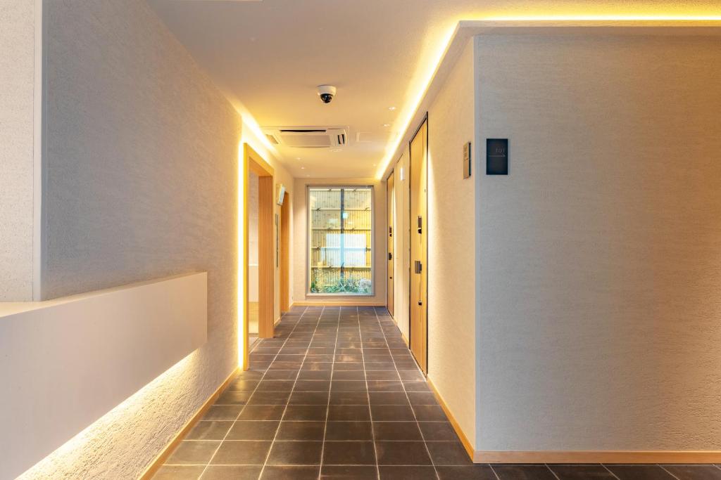 a hallway of a house with white walls and a tile floor at Dash Living Gojo in Kyoto