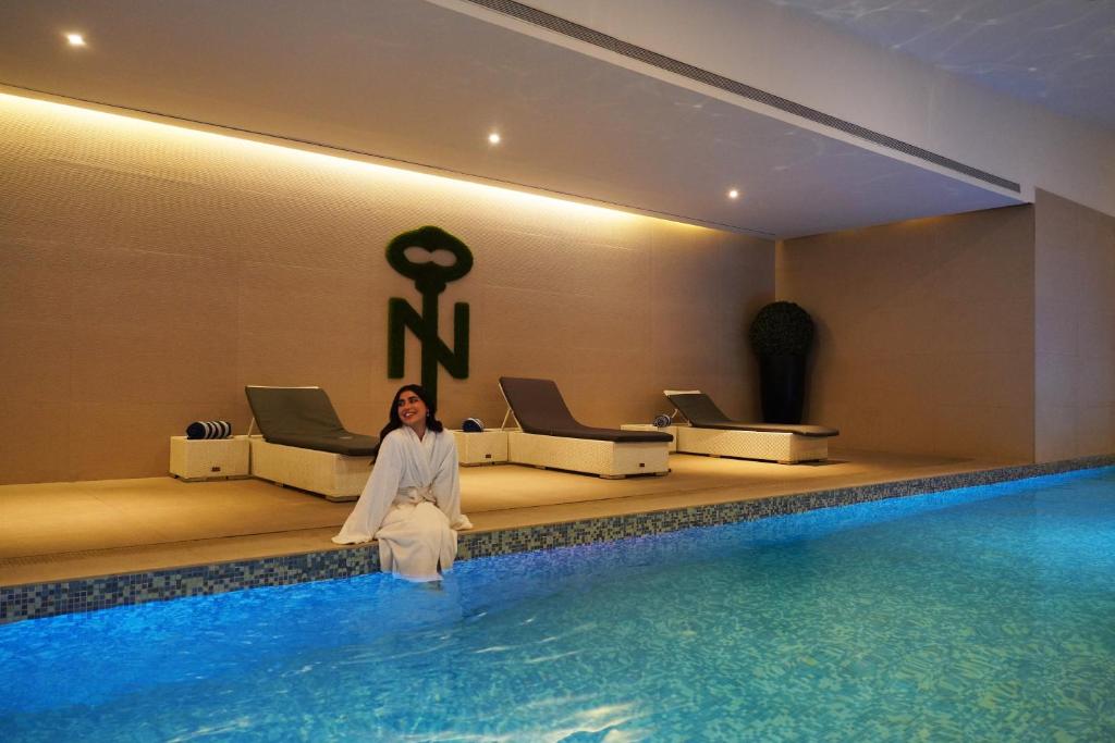 a woman in a white dress sitting next to a swimming pool at The Nishat Hotel Johar Town in Lahore