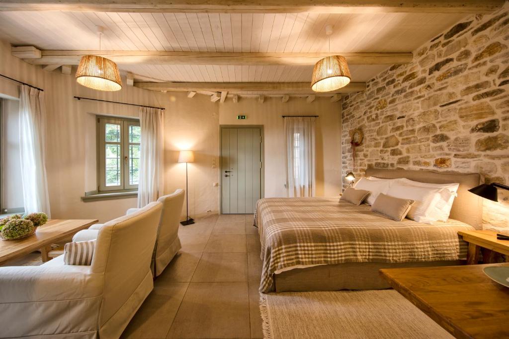 1 dormitorio con cama y pared de piedra en Amanita boutique hotel, en Tsagkarada