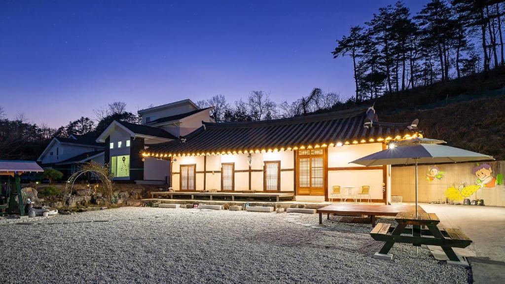 江陵市Gangneung ggabinejip hanok pension的一座带野餐桌和雨伞的建筑