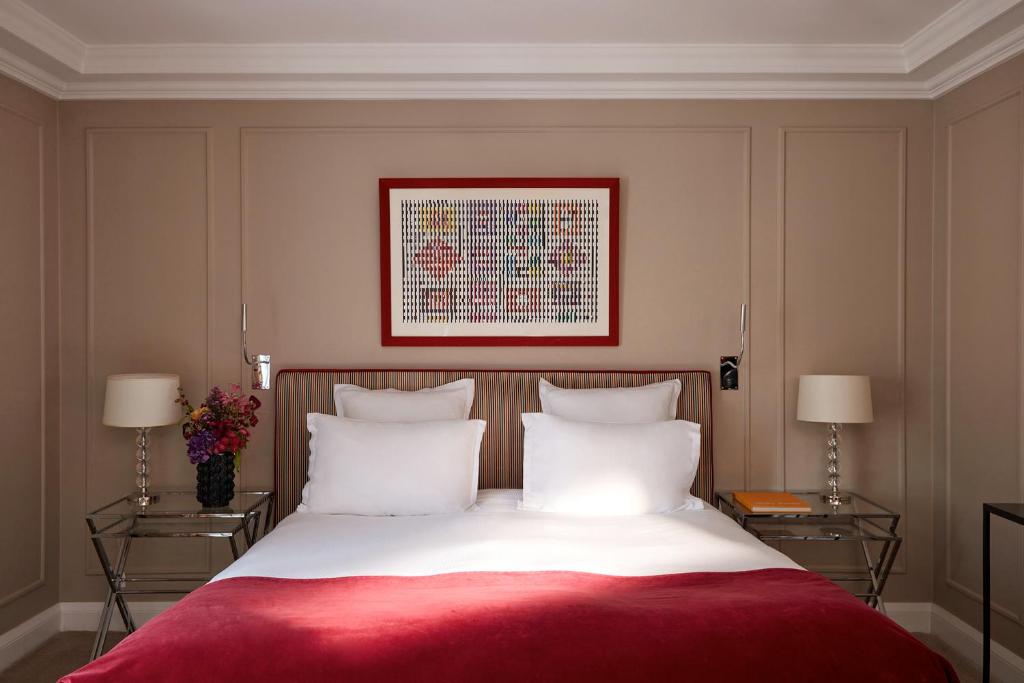 a bedroom with a bed with a red blanket and two lamps at Le Burgundy Paris in Paris