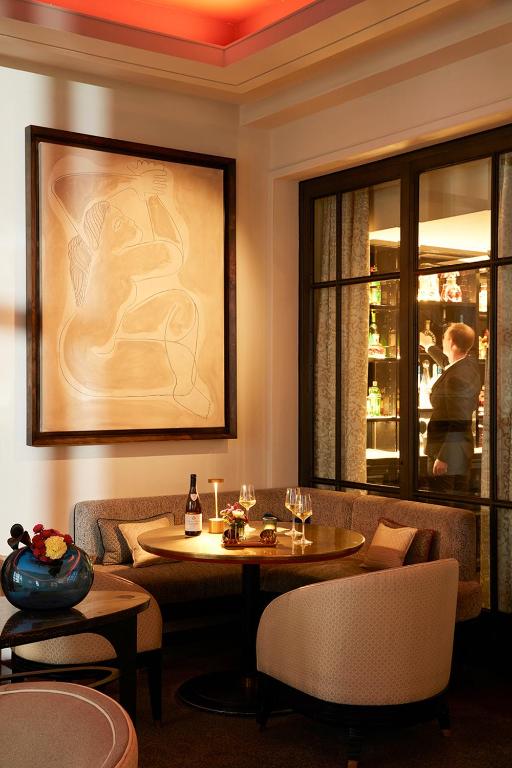 a dining room with a table and chairs and a painting at Le Burgundy Paris in Paris