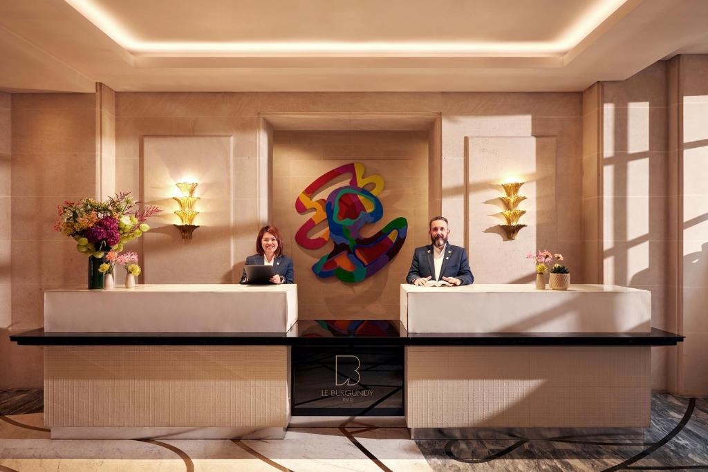 two people sitting at reception desks in a lobby at Le Burgundy Paris in Paris