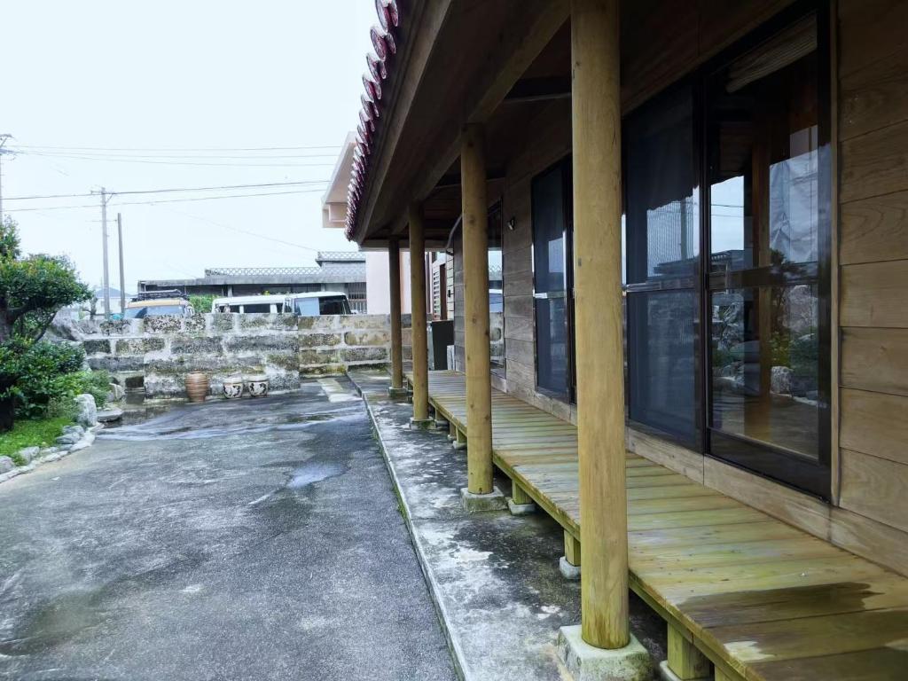 a wooden porch on a house with a building at 田舎の静かな古民家の悠水居 in Itoman