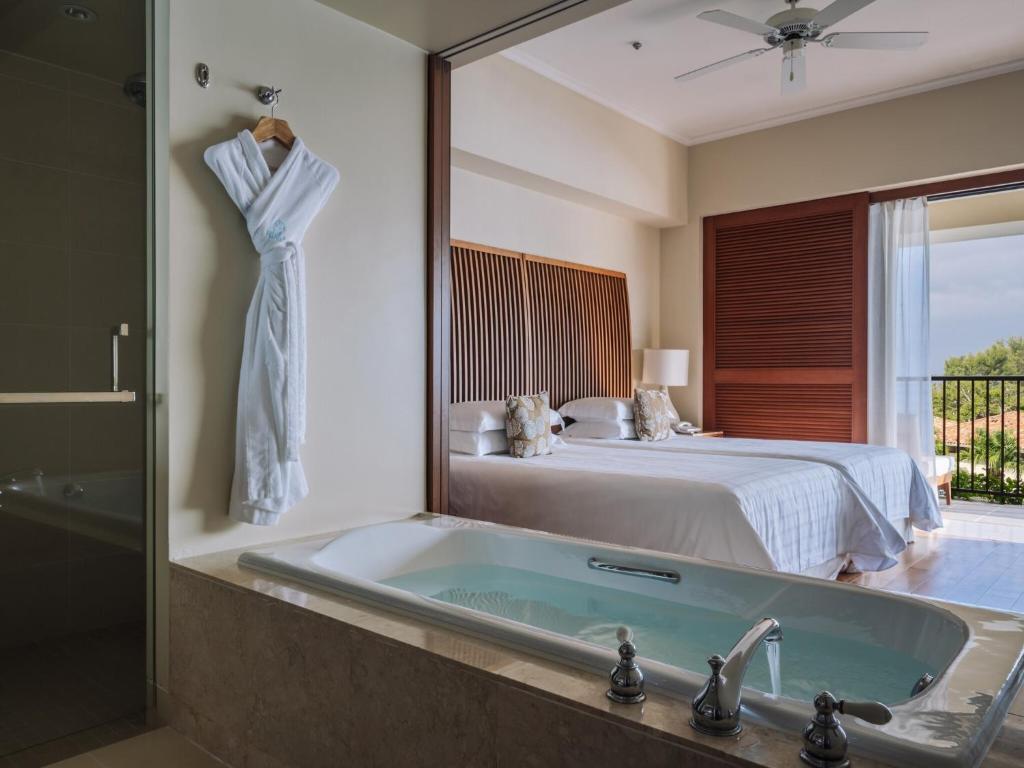 a bathroom with a tub and a bed and a mirror at The Terrace Club Wellness Thalasso At Busena in Nago