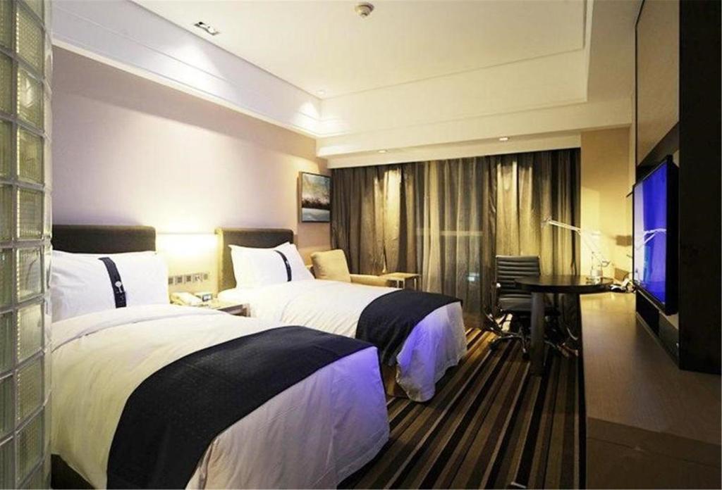 a hotel room with two beds and a television at Holiday Inn Express Shenyang Golden Corridor by IHG in Shenyang