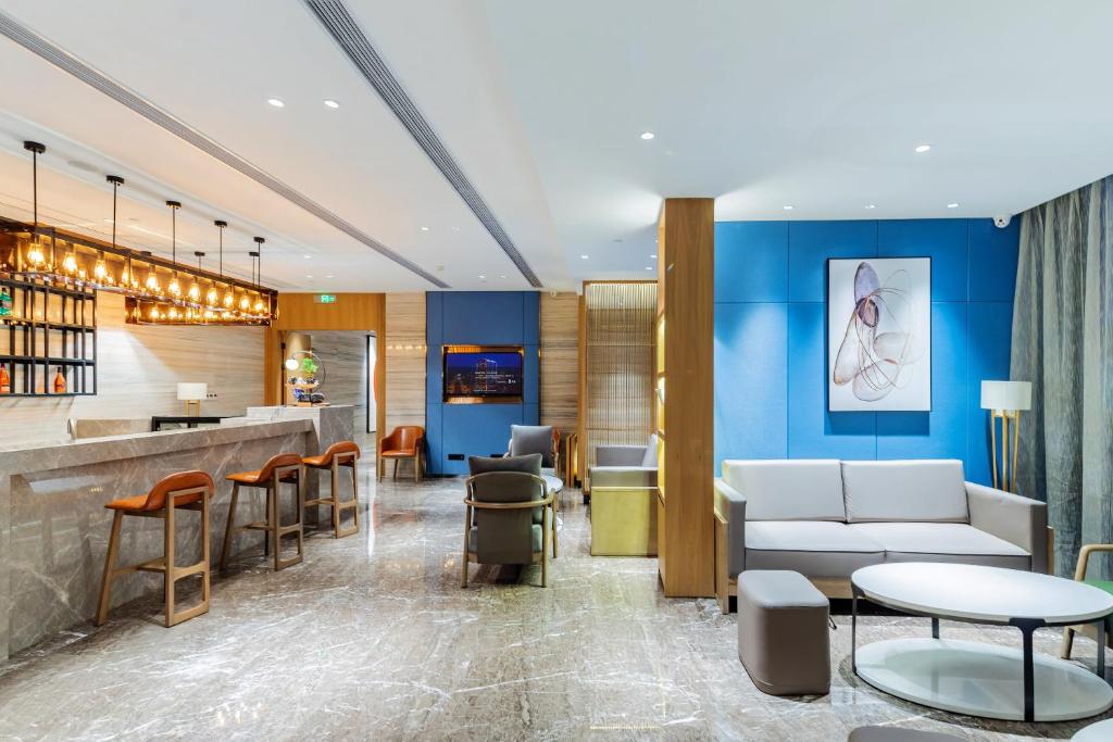 a lobby with a bar and tables and chairs at LIZ International Hotel Guangzhou Olympic Sports Center International Financial City Branch - Free Shuttle Bus to Canton Fair Complex During Canton Fair Period & Free Breakfast & Free Afternoon Tea & Free Midnight Snack in Guangzhou
