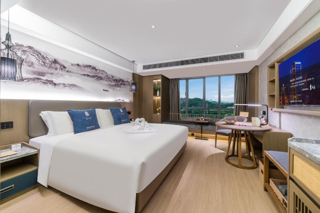 a bedroom with a large white bed and a desk at LIZ International Hotel Guangzhou Olympic Sports Center International Financial City Branch - Free Shuttle Bus to Canton Fair Complex During Canton Fair Period & Free Breakfast & Free Afternoon Tea & Free Midnight Snack in Guangzhou