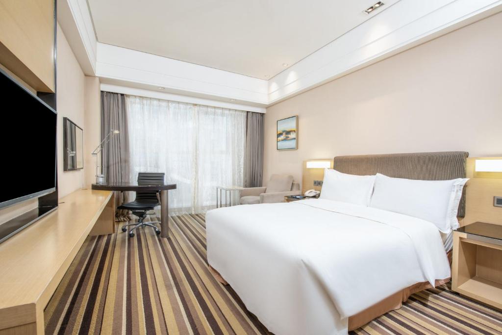 a hotel room with a large white bed and a desk at Holiday Inn Express Shenyang Golden Corridor by IHG in Shenyang