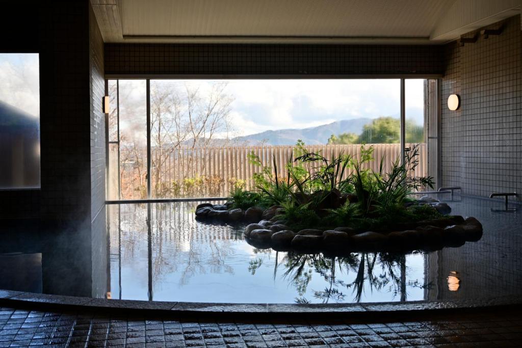 a large pool of water in a room with a large window at Hotel Laforet Shuzenji in Izu
