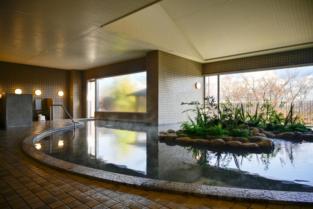a swimming pool in a building with a large window at Hotel Laforet Shuzenji in Izu