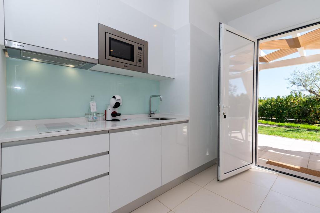 a kitchen with white cabinets and a microwave at Quinta Dos Perfumes in Tavira