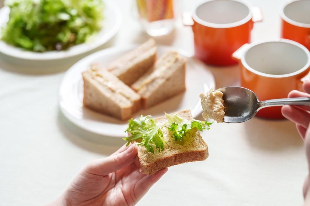 a person is holding a piece of bread with a spoon at Premier Hotel Cabin Shinjuku in Tokyo