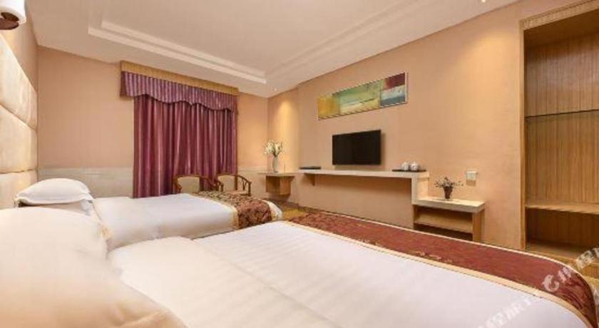 a hotel room with two beds and a television at Airport Liwan Hotel in Huadu