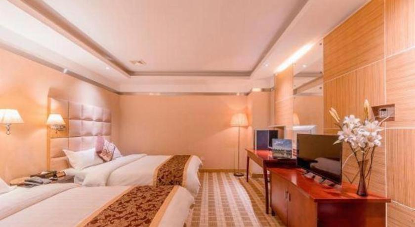 a hotel room with two beds and a desk at Airport Liwan Hotel in Huadu