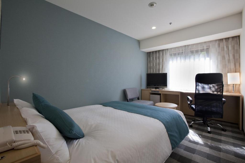 a bedroom with a bed and a desk and a chair at Hotel Granvia Wakayama in Wakayama