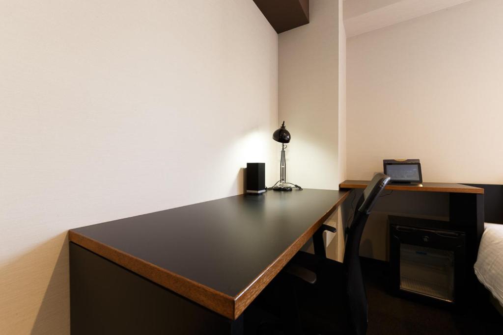 a room with a desk with a laptop and a bed at Hotel Citio Shizuoka in Shizuoka