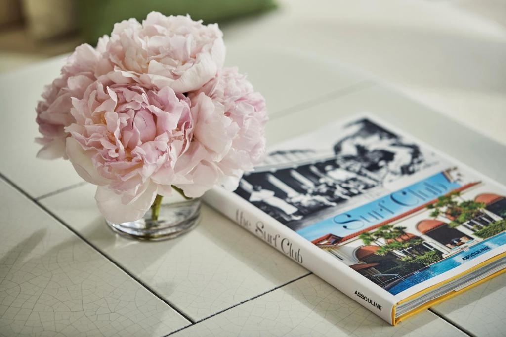 a vase with a pink flower next to a book at Four Seasons Hotel at The Surf Club in Miami Beach