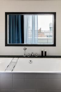 a white bath tub with a large mirror above it at The Mandala Berlin, a Member of Design Hotels in Berlin +37 photos