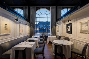 a restaurant with white tables and chairs and windows at Hotel Lungarno - Lungarno Collection in Florence +37 photos